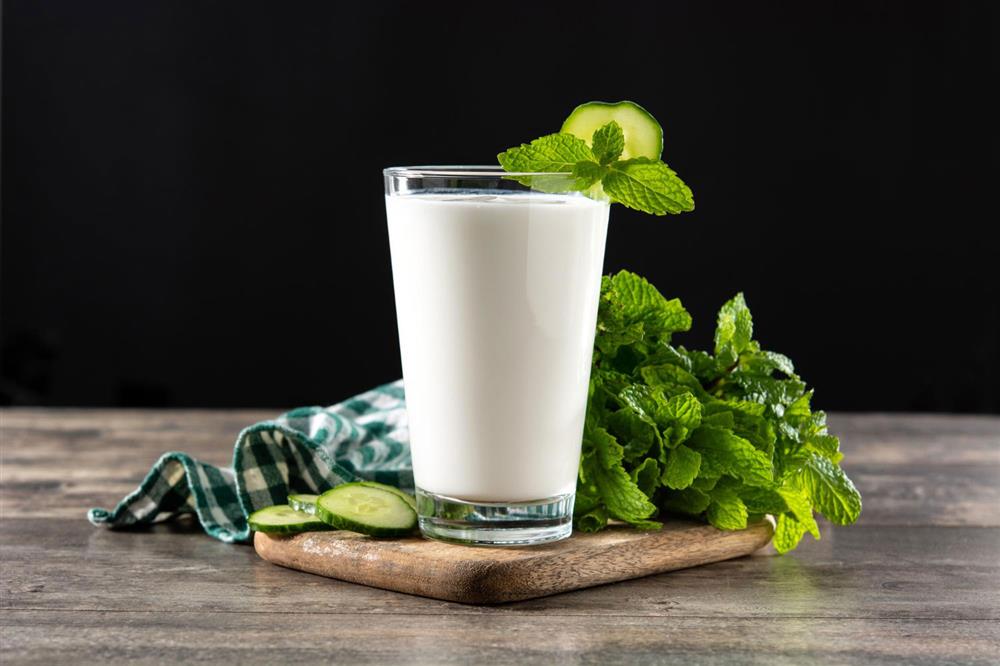 A glass of buttermilk (Ayran) with mint leaves and lemon slices on the side